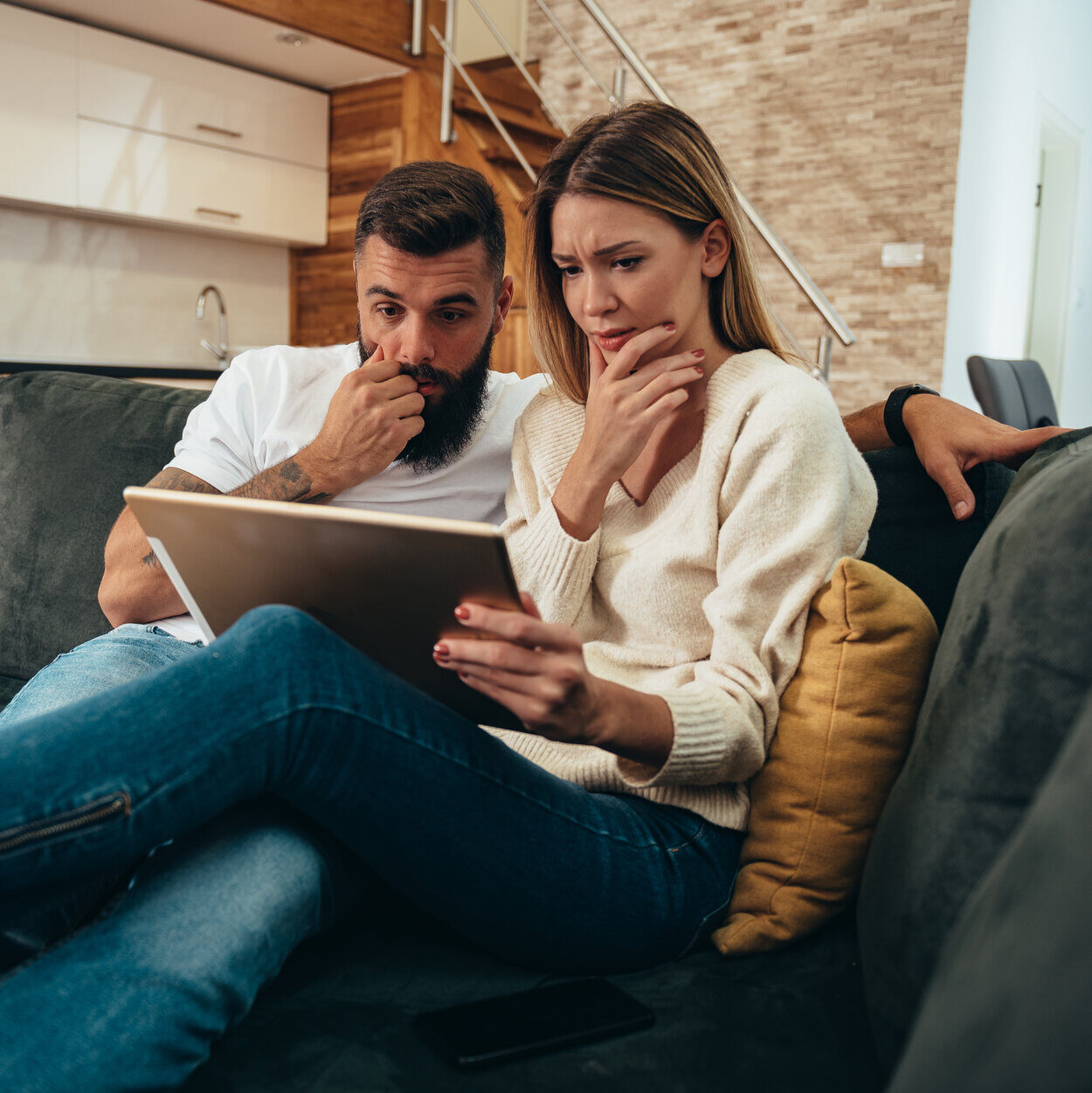 Shot of a young couple looking stressed while going over their finances on a digital tablet at home